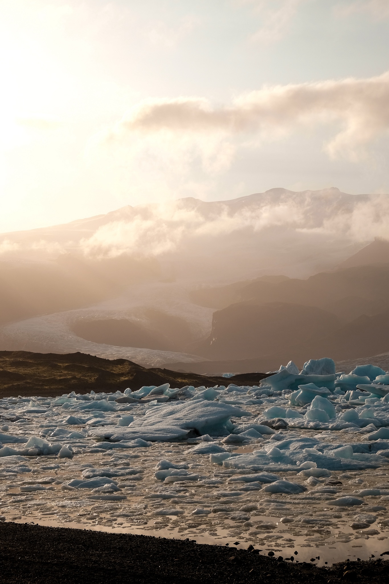 Glacier moving down a mountain into a glaciel lake with large chunks of floating ice