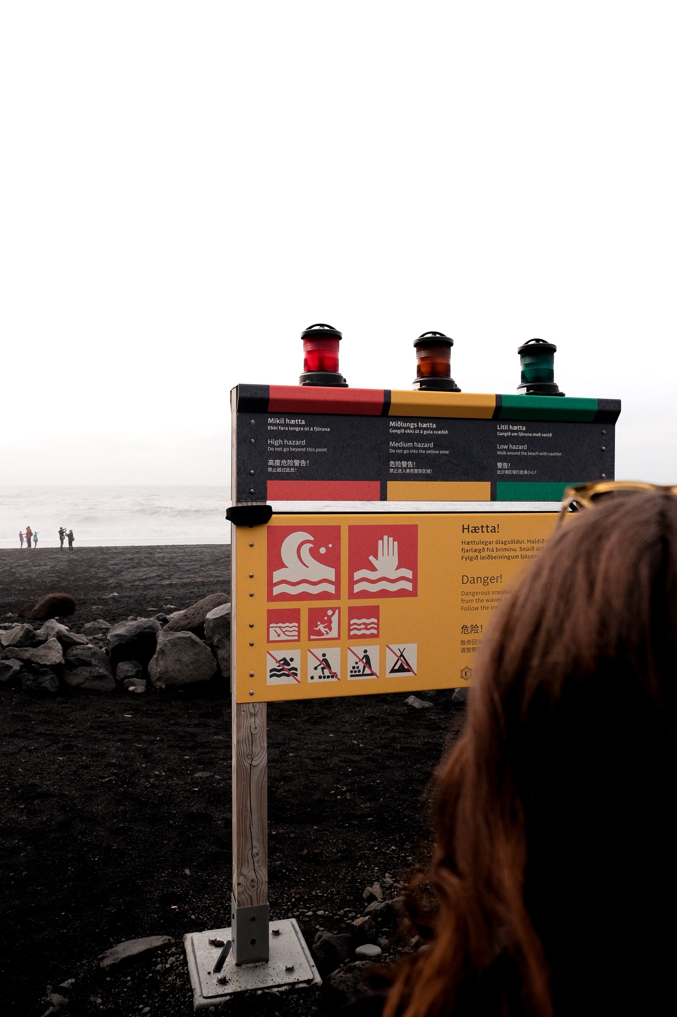 A green, yellow, and red light on a warning sign at the entrance to the black beach in Vik, Iceland