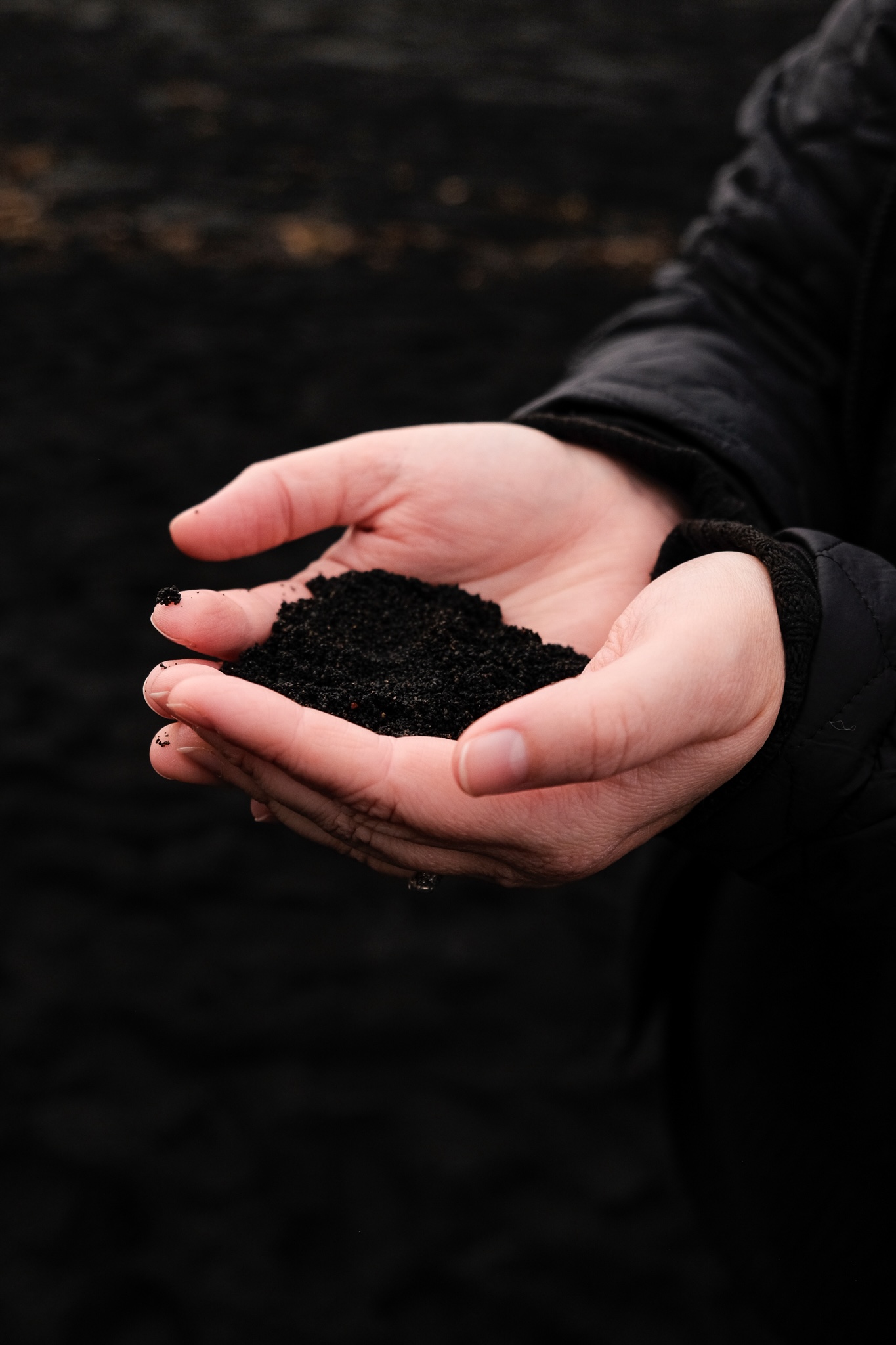 Black sand in Jenna's hands from the black beach in Vik, Iceland